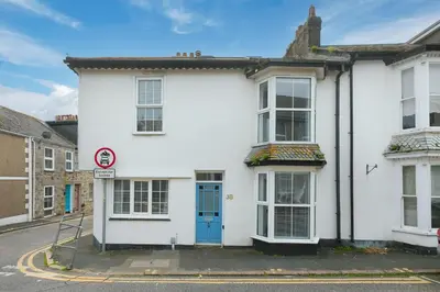 a white house with a blue door on a street at Floyd's in St Ives