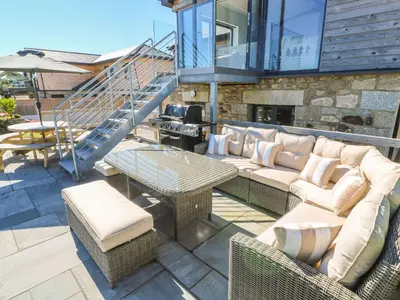 a patio with a couch and chairs and a staircase at Cedar Lodge in Carbis Bay