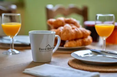 a table with two glasses of orange juice and pastries at Finest Retreats - Skylarks in Boscastle