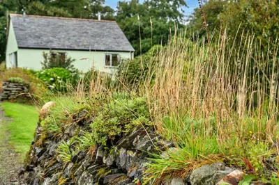 a stone wall with a house in the background at Finest Retreats - Skylarks in Boscastle