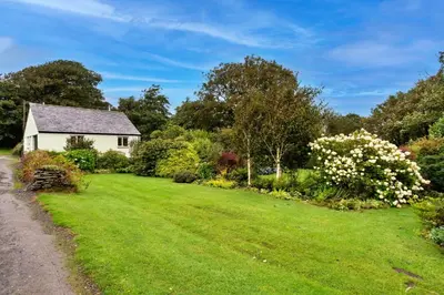 a garden with a white house and flowers at Finest Retreats - Skylarks in Boscastle