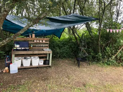 a blue tarp over a table with a kitchen under a tent at Rose in St Austell
