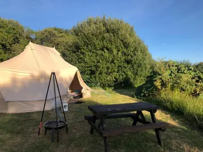 a tent with a picnic table and a bench at Rose in St Austell