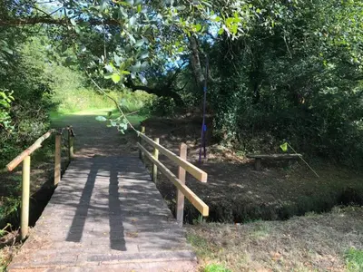 a wooden bridge over a path in a park at Rose in St Austell
