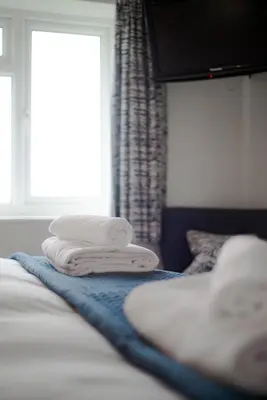 three towels sitting on top of a bed with a window at Trevose Golf and Country Club in Padstow