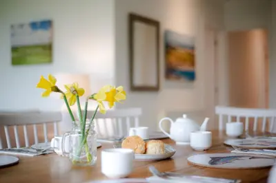 a wooden table with a vase of flowers and food on it at Trevose Golf and Country Club in Padstow