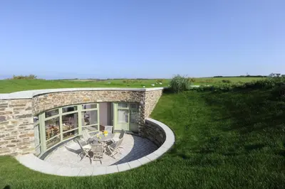 a stone house with a patio and a lawn at Trevose Golf and Country Club in Padstow