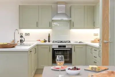 a kitchen with green cabinets and a glass of wine at 4 Valley View in Looe