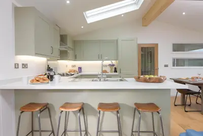 a kitchen with three bar stools and a sink at 4 Valley View in Looe