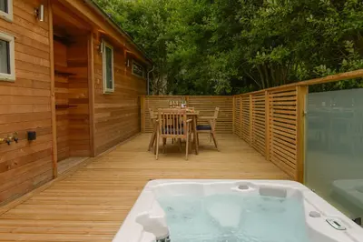 a hot tub on a wooden deck with a table at 4 Valley View in Looe