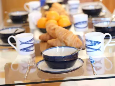 a table with cups and croissants and a plate of food at Luxurious apartment, 180° beach views & parking in St Ives