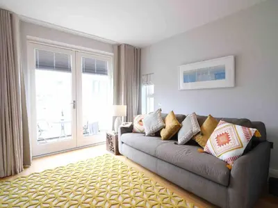 a living room with a couch and a large window at Luxurious apartment, 180° beach views & parking in St Ives