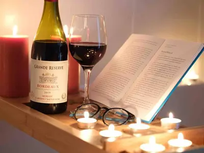 a bottle of wine and glasses on a table with a book at Luxurious apartment, 180° beach views & parking in St Ives
