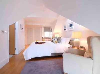 a large white bedroom with a bed and a couch at Luxurious apartment, 180° beach views & parking in St Ives