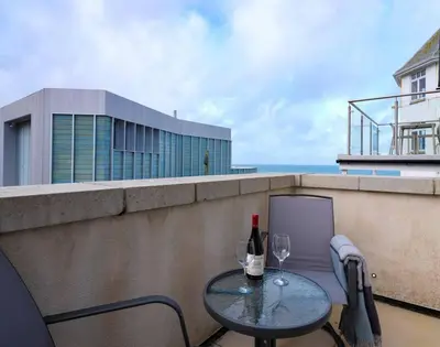 a table with two glasses and a bottle of wine on a balcony at Luxurious apartment, 180° beach views & parking in St Ives