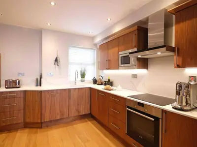 a large kitchen with wooden cabinets and a window at Luxurious apartment, 180° beach views & parking in St Ives