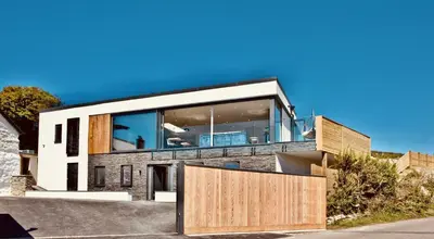 a house with a large window and a wooden gate at Rockpools in Porth