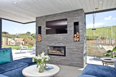 a living room with a stone fireplace with a tv at Rockpools in Porth