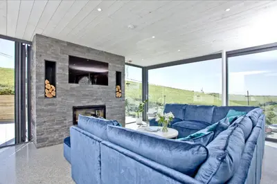 a living room with blue couches and a fireplace at Rockpools in Porth