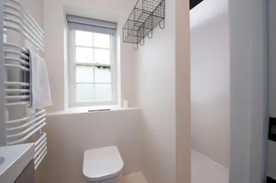 a white bathroom with a toilet and a window at Watersend in Porth
