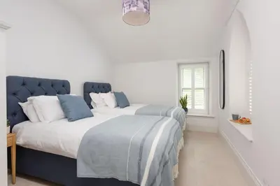 a white bedroom with a blue and white bed at Watersend in Porth
