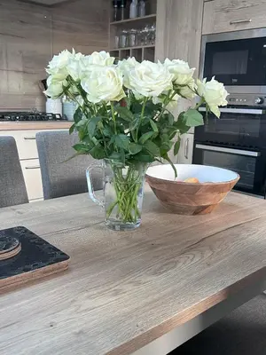 a vase of white roses sitting on a table at Sandy Toes, Padstow in Padstow