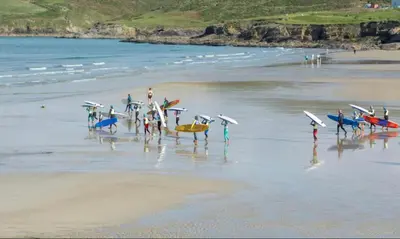 a group of people standing on a beach with surfboards at Sandy Toes, Padstow in Padstow
