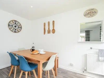 a dining room with a wooden table and blue chairs at The Old Forge in Saltash