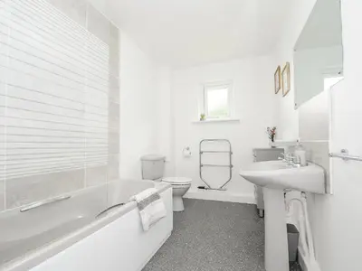 a white bathroom with a tub and a toilet and a sink at The Old Forge in Saltash