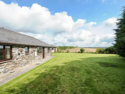 a stone house with a large yard next to a building at The Old Forge in Saltash