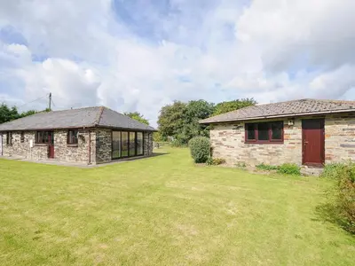 a stone house with a large yard next to a building at The Old Forge in Saltash