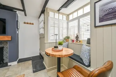 a room with a table and a chair and windows at Luxury Couple's Getaway with River Views and Parking in Polperro