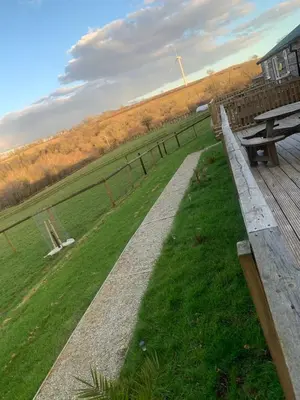 a park with a wooden bench and a fence at Brook Lodge in Liskeard