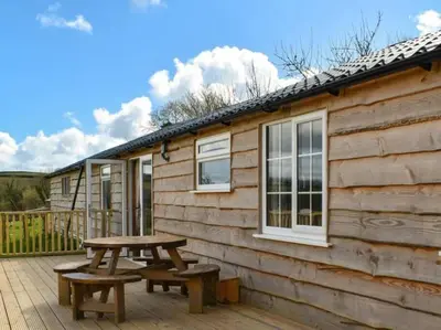 a picnic table and benches on the deck of a cabin at Brook Lodge in Liskeard