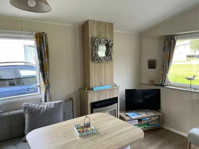 a living room with a table and a tv at Cornish Crantock Holiday Sandy Toes in Crantock