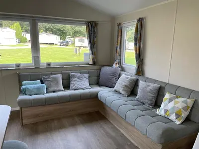 a couch in a living room with windows at Cornish Crantock Holiday Sandy Toes in Crantock