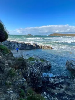 a person walking on the rocks near the ocean at Cornish Crantock Holiday Sandy Toes in Crantock