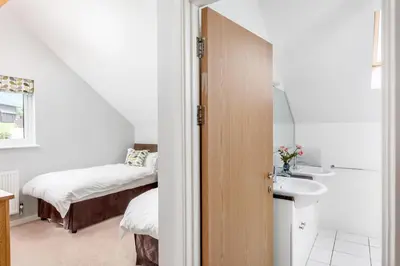 a bathroom with a sink and a bedroom with a bed at Sunbow at Retallack Resort in Saint Columb Major