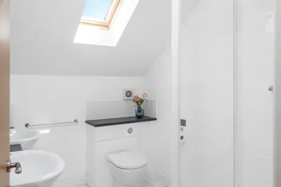 a white bathroom with a toilet and a sink at Sunbow at Retallack Resort in Saint Columb Major
