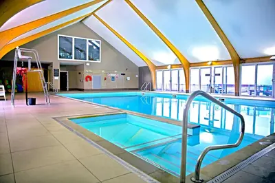a large swimming pool with blue water in a building at Sunbow at Retallack Resort in Saint Columb Major