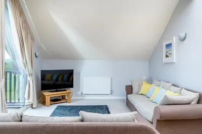 a living room with a couch and a tv at Sunbow at Retallack Resort in Saint Columb Major