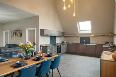 a large living room with a table and a kitchen at Finest Retreats - Beach House in Newquay