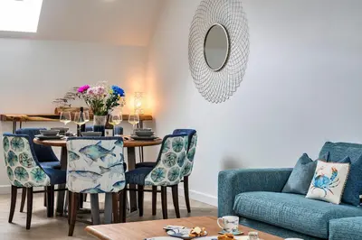 a living room with a table and a blue couch at Finest Retreats - Lobster House in Newquay
