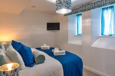 a bedroom with a large bed with blue pillows at Finest Retreats - Lobster House in Newquay