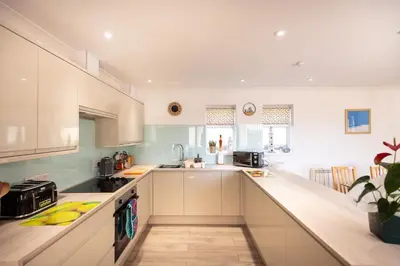 a kitchen with white cabinets and a counter top at Mermaid - Pet Friendly Self Catering Holiday Cottage Hayle in Hayle