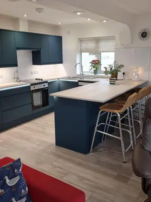a kitchen with blue cabinets and a large island at Dolphin - Pet Friendly Self Catering Holiday Cottage Hayle St Ives Bay in Hayle