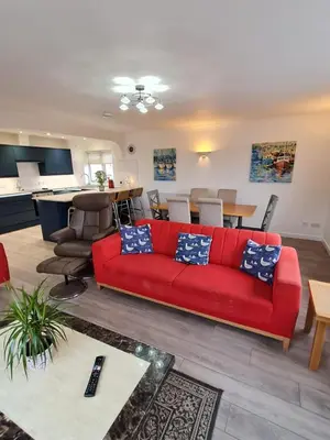 a living room with a red couch and a table at Dolphin - Pet Friendly Self Catering Holiday Cottage Hayle St Ives Bay in Hayle