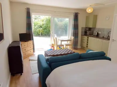 a living room with a blue couch and a kitchen at Wadebridge Whitecross Studio 2 in Wadebridge