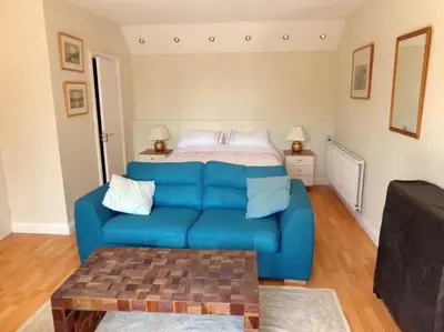 a blue couch in a living room with a bed at Wadebridge Whitecross Studio 2 in Wadebridge
