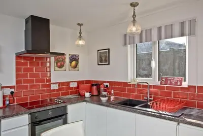 a kitchen with a sink and a red brick wall at Hill Head Cottage in Saint Columb Major